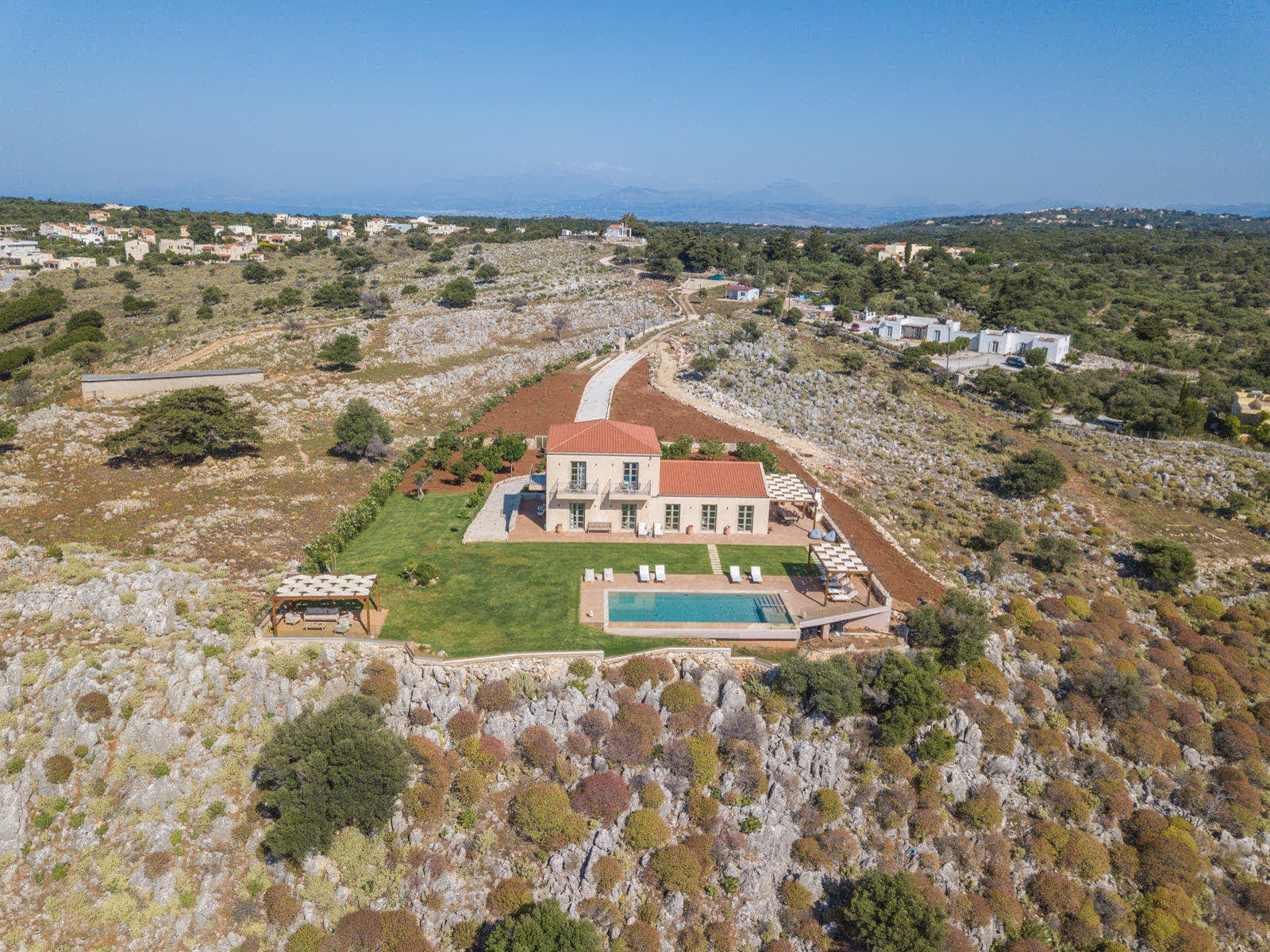 Aerial view of Aquila Villa on the rocky hilltop above Drapanos, with the infinity pool and lawn