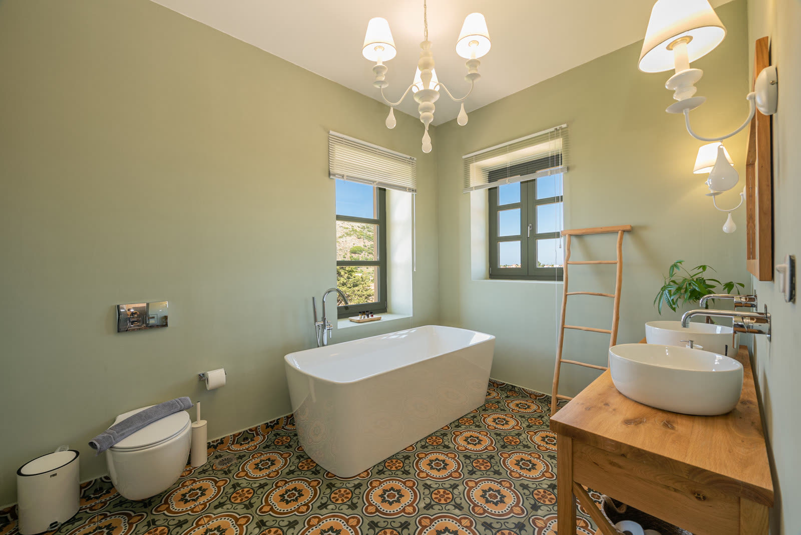 Ensuite bathroom with freestanding bathtub, double vessel sinks and patterned floor tiles
