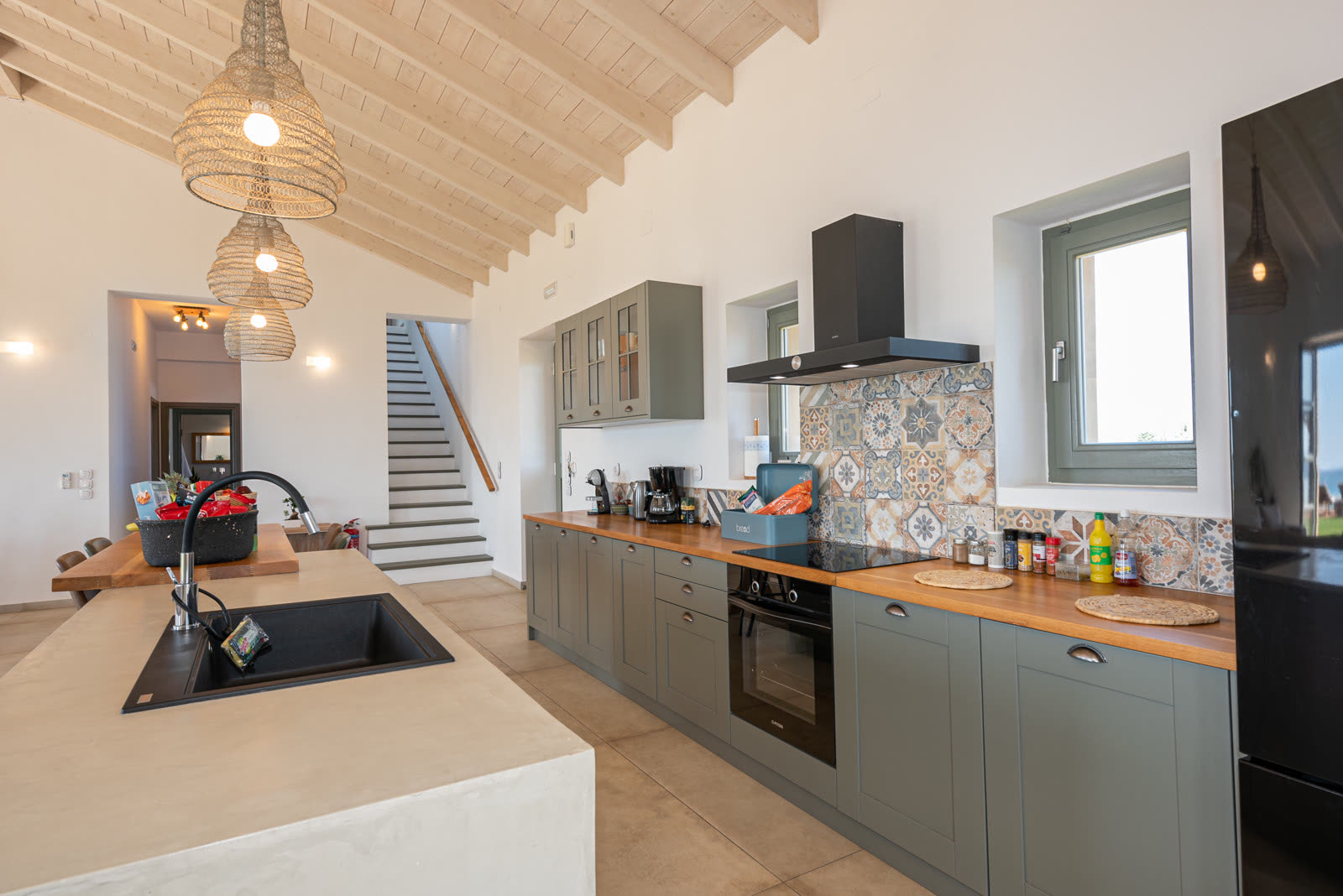 Kitchen with island, sage cabinetry and vaulted wood ceiling