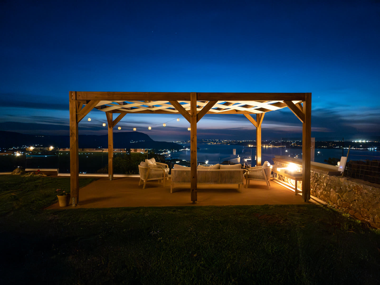 Pergola lounge at night overlooking the coast and village lights