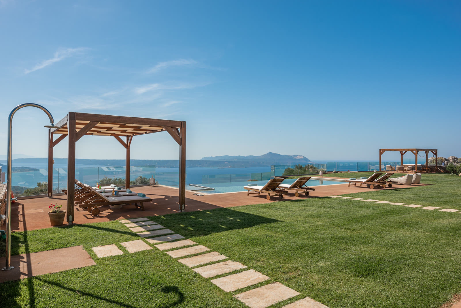 Infinity pool, lawn, pergolas and the sea beyond Aquila Villa