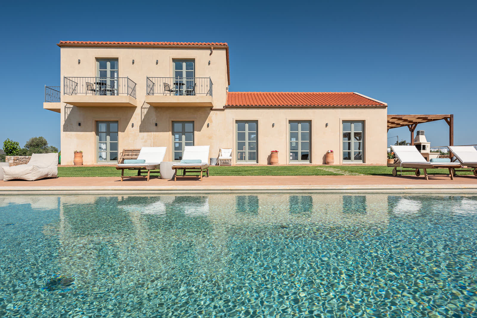 Two-storey villa seen across the swimming pool in daylight